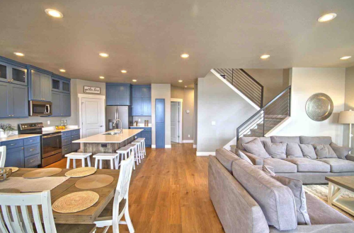 Modern open-concept kitchen and living area with blue cabinets, a large island, and a cozy gray sofa.